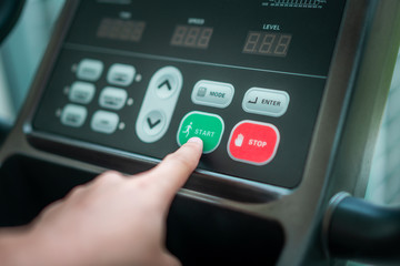 Start running - Hand pressing start button on treadmill control panel. Healthy lifestyle concept.