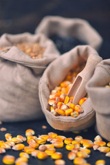 Small bags with various grains and cereals on wooden table, top view, copy space