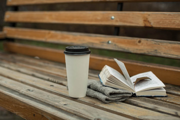 a book and a glass of coffee in the park on a bench