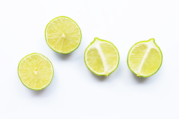 Ripe limes with green leaves on white.