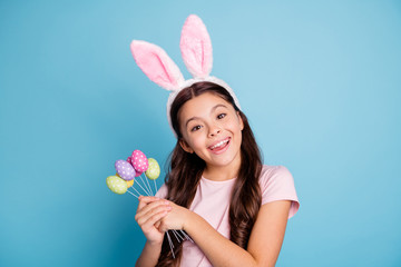 Closeup portrait of nice positive cheerful enjoying fest season girl holding a lot of painted in different colors easter eggs looking at camera isolated pastel background