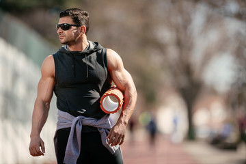 Fototapeta premium Athlete wearing sunglasses, holding a foam roller, getting ready for a workout.