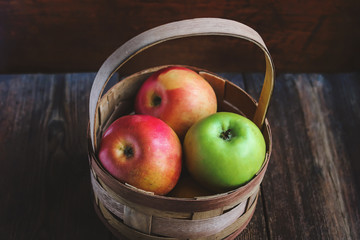 apples in a basket on a wooden background.