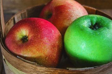 apples in a basket. in drops of dew. on a wooden background.