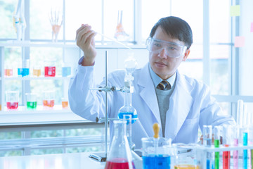 Fototapeta premium Scientist dropping liquid into blue test tube.
