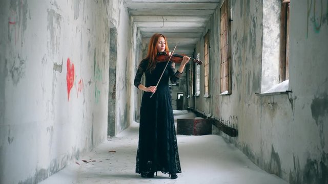 Rundown corridor with a redhead woman playing the violin