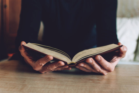 Man holding Open book in hands. Male hands hold a hardcover book. Education, literature, knowledge, reading concept. Copy space
