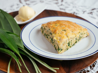 Plate with home made savory wild garlic scones and some wild garlic leaves.