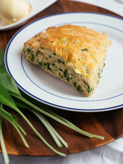 Plate with home made savory wild garlic scones and some wild garlic leaves.