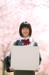 桜の前でメッセージボードを持つ中学生