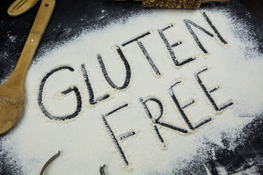 Gluten free word written on flour. Table wooden background