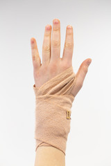 Closeup view of a person’s bandaged hand isolated on a white background.