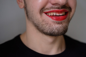 Obraz premium Man with a red lipstick on smiling. Lips and beard close-up. Lgbt comunity. Transsexual guy. Transgender.