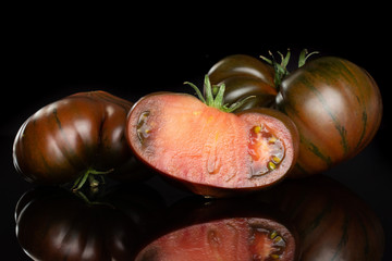 Fototapeta premium Group of two whole one half of meaty fresh tomato primora isolated on black glass