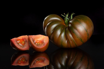 Group of one whole two slices of fresh tomato primora isolated on black glass