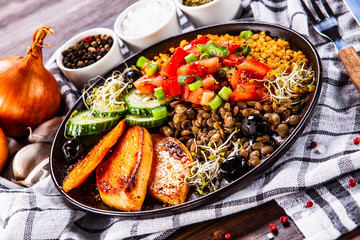 Groats with lentils and vegetables on wooden table