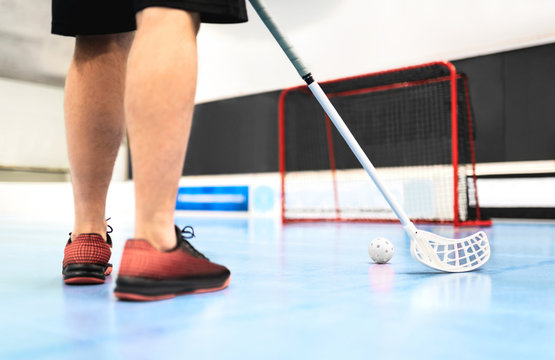 Back View Of Floorball Player Training With Stick, Ball And Goal On Court. Man Playing In Floor Hockey Arena.