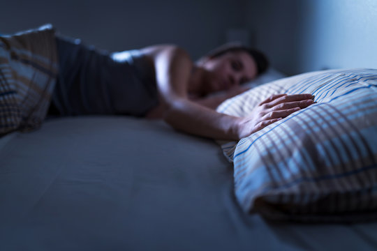 Single Woman Sleeping Alone In Bed At Home. Lonely Lady Missing Husband Or Boyfriend. Hand On Pillow. Solitude, Infidelity Or Heartbreak Concept. Loneliness And Sorrow After Break Up Or Divorce.