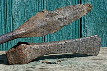 one long old iron spear and battle ax lie on a gray table against a green wall