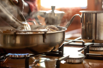 Closeup view of silver pots and pans cooking food a stovetop