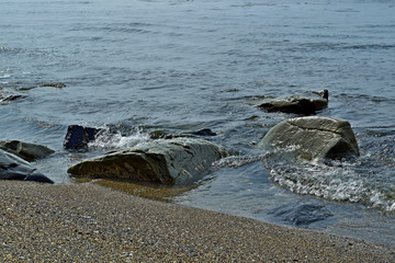 coast of the bay with rubble stones in the water