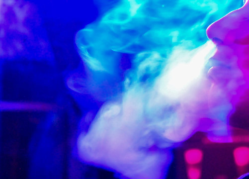 Joven echando humo por la nariz y boca por inhalar cachimba, distancia social 