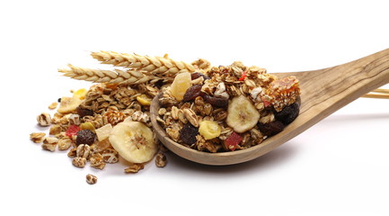 Crunchy tropical muesli pile mix with banana, pineapple, papaya slices, raisins and wheat ears with wooden spoon isolated on white background