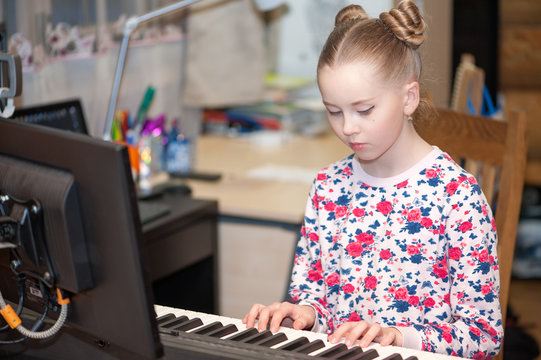 A girl plays the electronic piano at home.