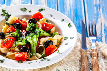 Pasta with herbs and vegetables on wooden background