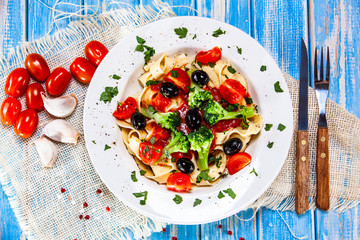 Pasta with herbs and vegetables on wooden background