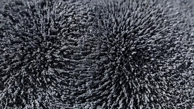 The magnetic field affects iron shavings and powder. Magnet and electricity. Abstraction and texture in gray background.