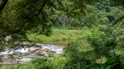 boy riding motorcycle through river road