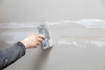 Worker aligns the walls with plaster. Repair in the house