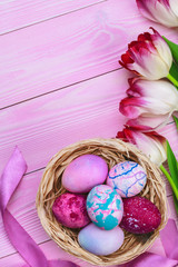 Beautiful Easter composition with decorated eggs and flowers on pastel wooden background