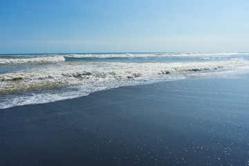 Black volcano sand beach and blue indian ocean in the east cost of Bali island