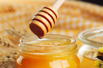 Honey background. Sweet honey in glass jar on wooden background.