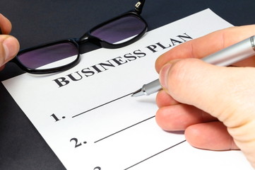 Strategy business plan with pen, glasses and hand on black table.