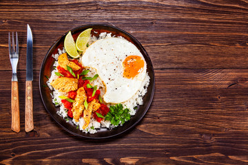 Grilled meat, white rice,fried egg vegetables on wooden table