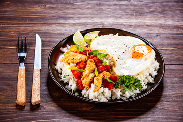Grilled meat, white rice,fried egg vegetables on wooden table