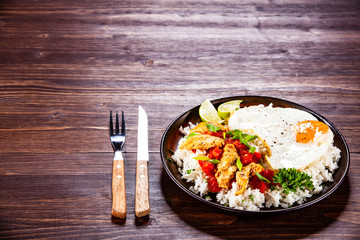 Grilled meat, white rice,fried egg vegetables on wooden table