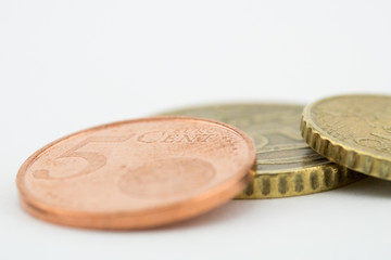 Coins of five euro cents, fifty euro cents and ten euro cents, white background.