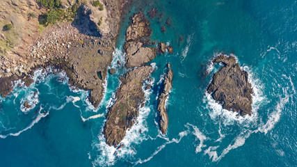 aerial shot of waves hitting rocks