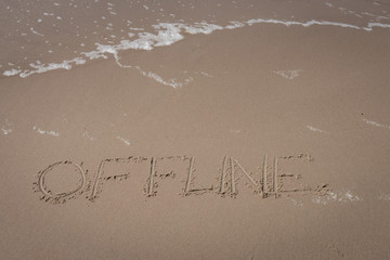 Fototapeta premium The word “offline” written in the sand symbolizing a time-out
