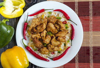 chicken in sweet and sour sauce and rice with vegetables on a white plate close-up Chinese cuisine