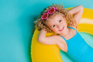 Cute girl in swimsuit holding swimming circle. Isolated on blue background .Summer holidays - pretty girl with inflatable ring 