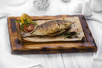 Spicy grilled fish seasoned with pepper on a board