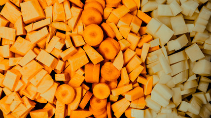 Sliced orange vegetables, carrots and pumpkins, colored background.