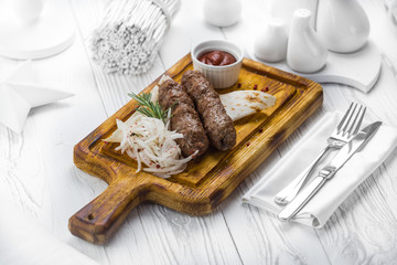 Beef sausages with onions and tomato dipping sauce on a board