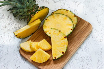 Sliced pineapple on a wooden board on a white background. Pineapple pieces of various sizes