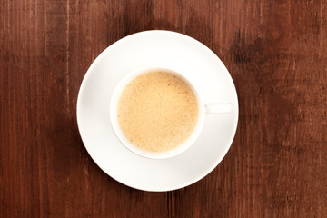A cup of coffee shot from above on a dark rustic wooden background with copyspace